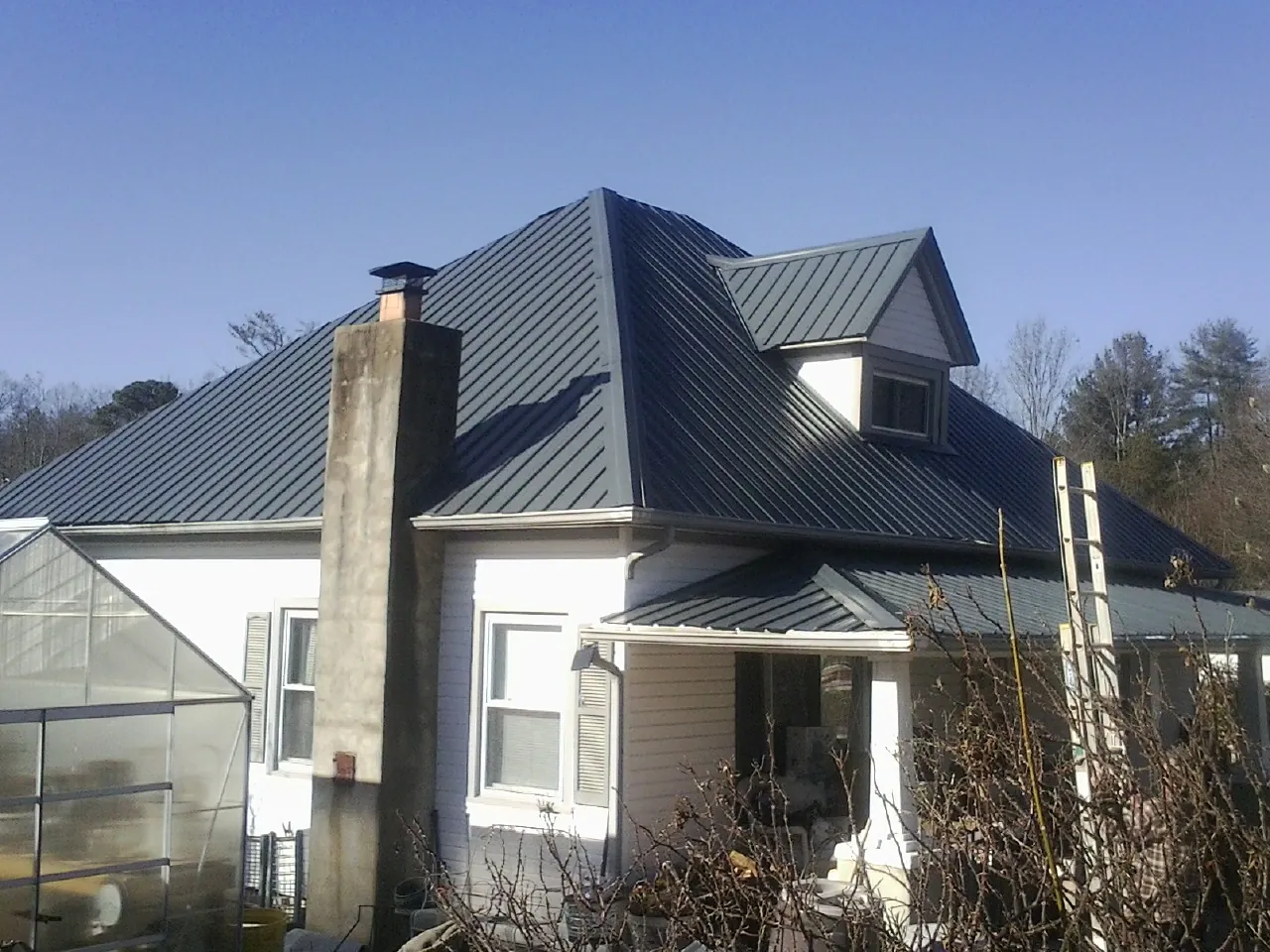Dark blue standing seam metal roof on a white farmhouse with dormer — Slate & Tile Roof Repair by Roofing Brothers in Stonington