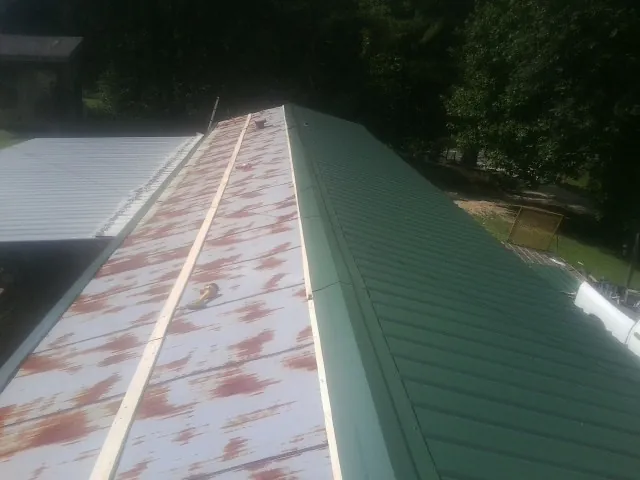 Old rusted panels beside newly installed green metal roofing — Wind Damage Roof Repair by Roofing Brothers in Stonington