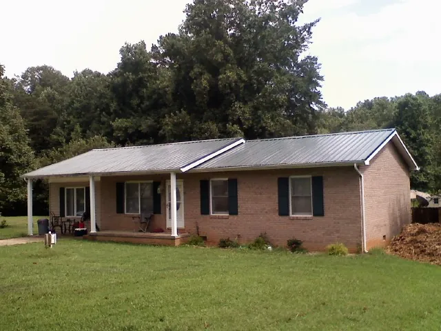 Gray metal roof on a brick ranch house with a side carport in Stonington