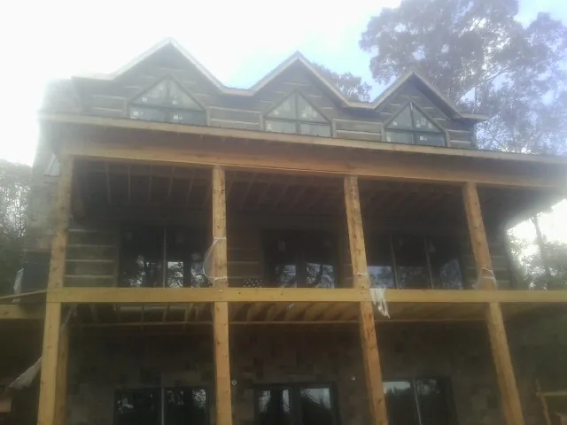 Dormers and porch framing on a large log home under construction — Roof Coating work by our crew in Stonington