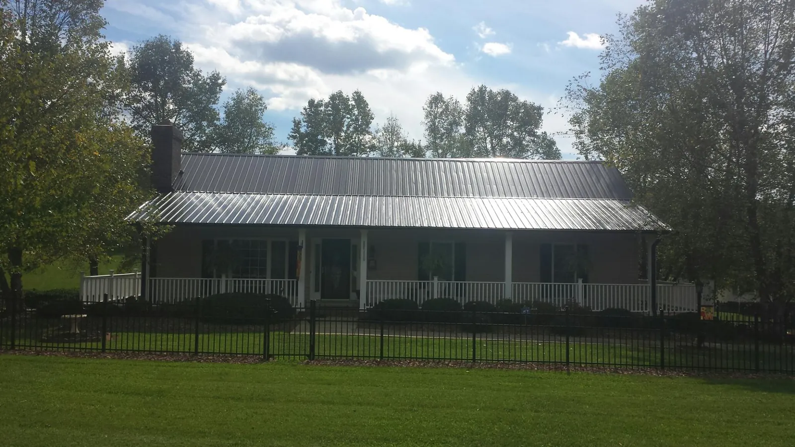 Gray metal roof on a brick ranch with a full width front porch — Gutter Guard Installation work by our crew in Stonington