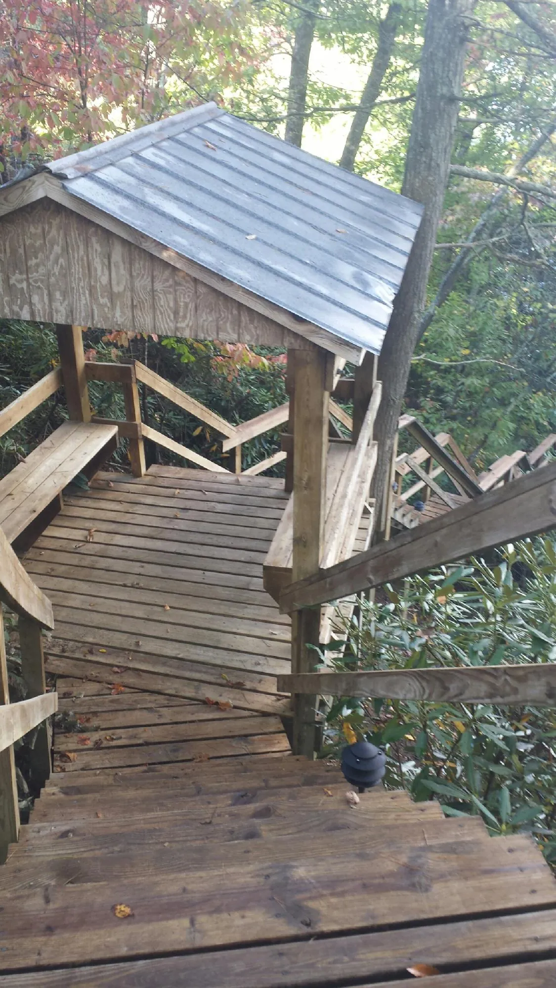 Metal roofed shelter over wooden steps on a wooded walkway — Skylight Repair & Installation work by our crew in Stonington
