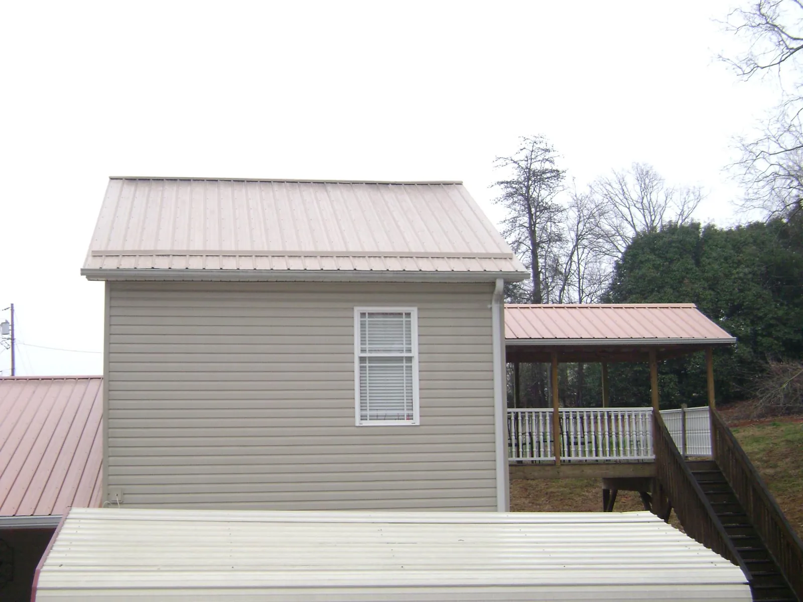 Tan metal roofs on a two story addition and attached porch, from a Roof Replacement job in Stonington