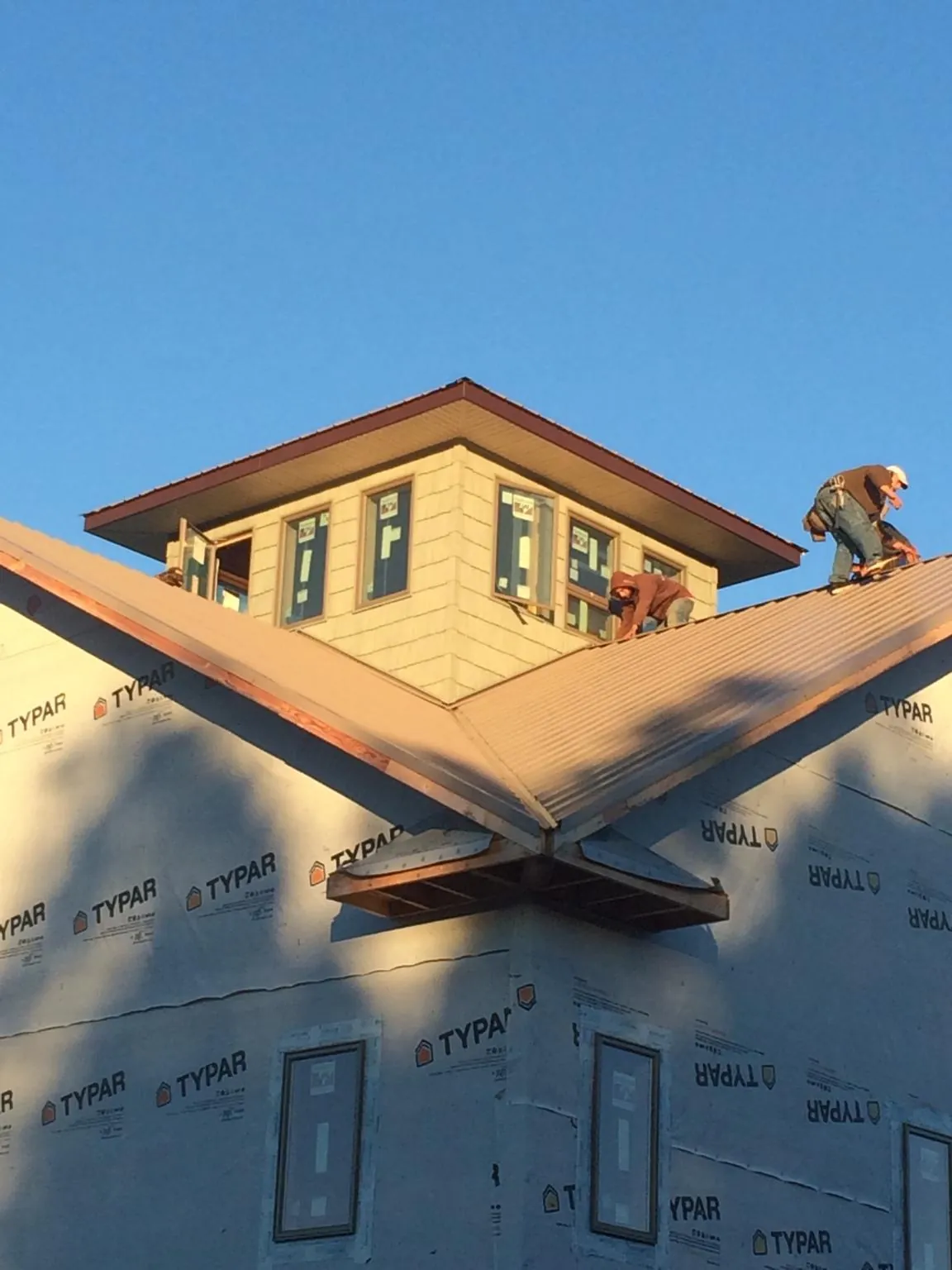 Roofers working around a rooftop cupola on a new metal roof at sunset — Roof Waterproofing in Stonington by Roofing Brothers